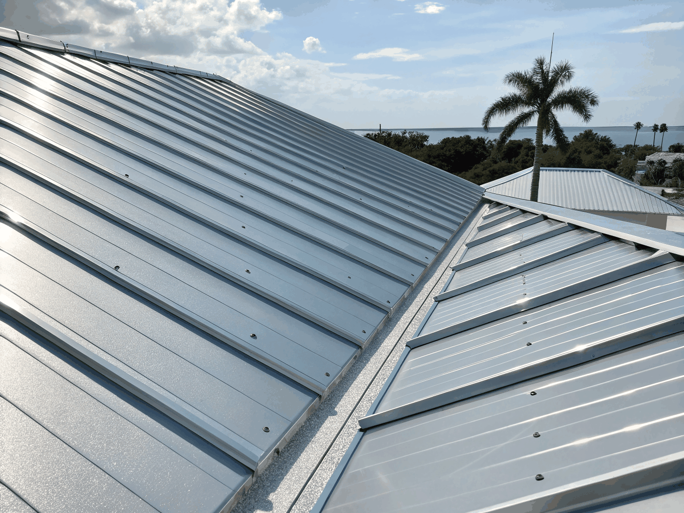 Roofing crew installing durable standing-seam metal roofing on a coastal residence